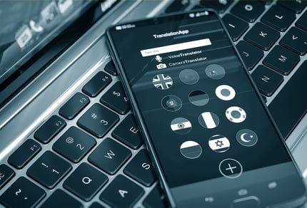 Smartphone mit Sprachen-Icons auf Laptop-Tastatur