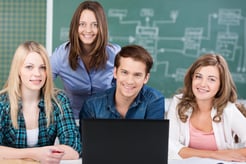 Attractive middle-aged woman teacher posing with a group of her teenage students in a college classroom-1