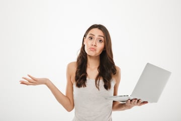 photo-of-upset-woman-with-long-brown-hair-throwing-up-hands-and-expressing-confusion-while-holding-silver-personal-computer-isolated-over-white-wall